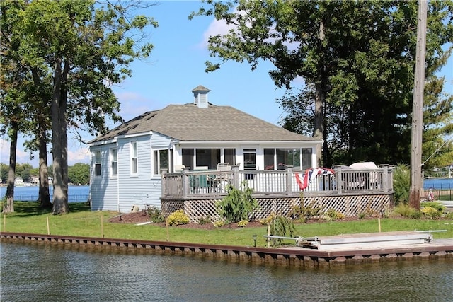 rear view of property with a deck with water view and a yard