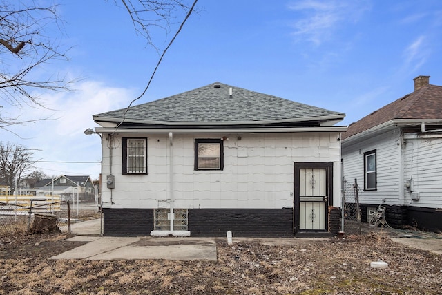 rear view of house with roof with shingles and fence