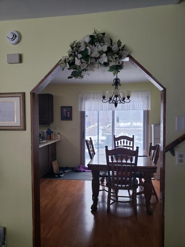 dining room with dark wood-type flooring and an inviting chandelier