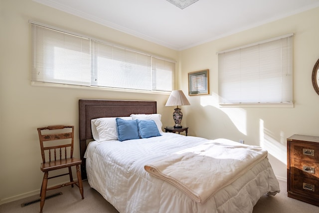 bedroom with crown molding, baseboards, visible vents, and light colored carpet