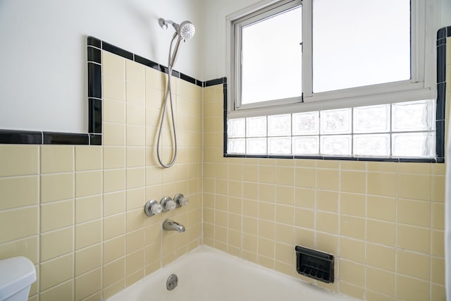 bathroom with a tub, a wealth of natural light, and toilet