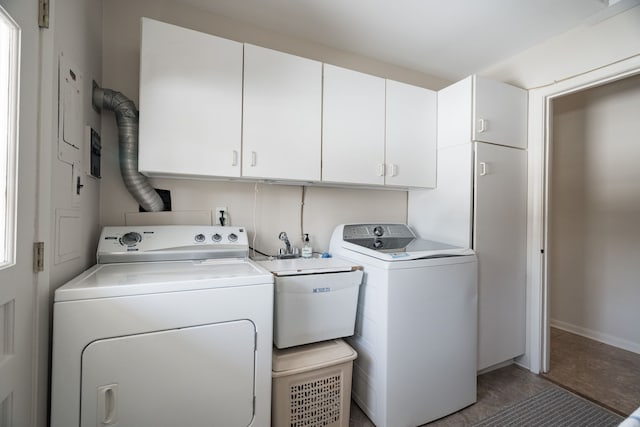 clothes washing area with washing machine and dryer, cabinet space, and a sink