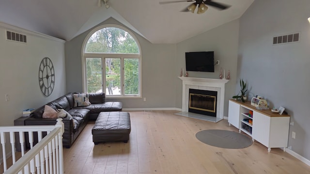 living room featuring ceiling fan, high vaulted ceiling, a fireplace, and light hardwood / wood-style floors