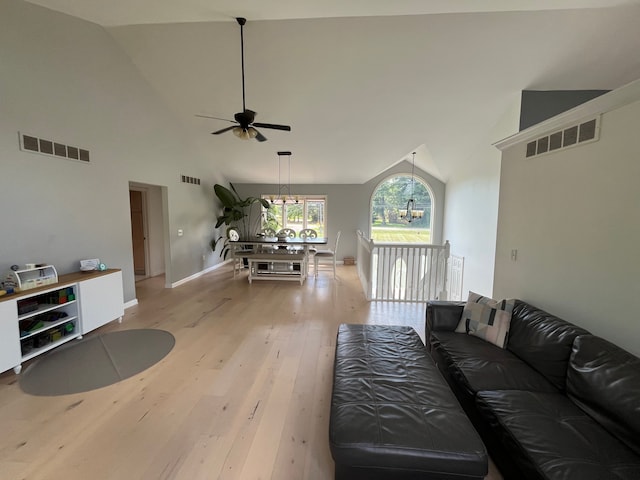 living room with high vaulted ceiling, ceiling fan with notable chandelier, and light wood-type flooring