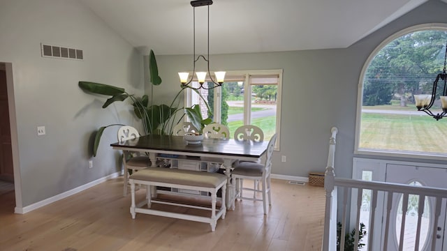 dining space with lofted ceiling, light hardwood / wood-style flooring, and a chandelier