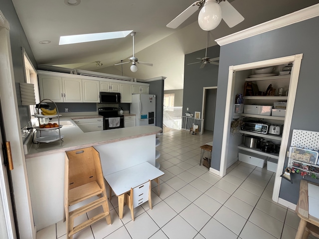 kitchen with black appliances, white cabinetry, a kitchen bar, light tile patterned floors, and kitchen peninsula