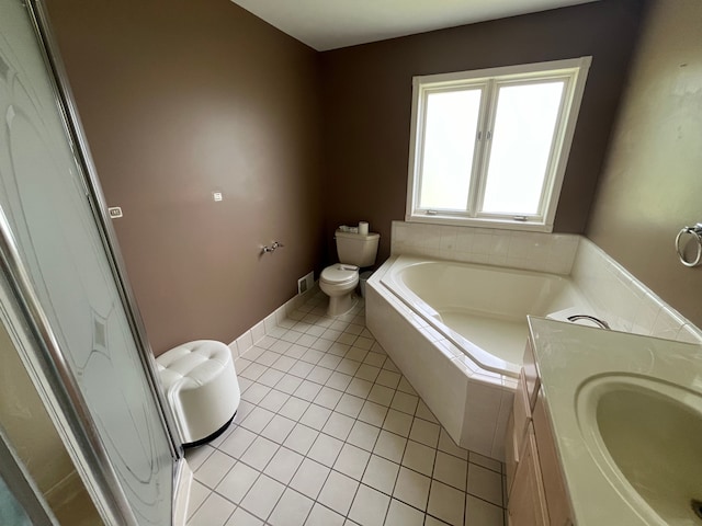 bathroom with tile patterned flooring, vanity, tiled bath, and toilet