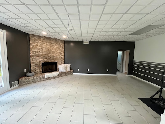 basement with a brick fireplace and a drop ceiling