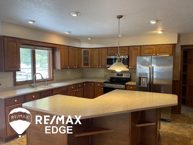 kitchen with a kitchen island, appliances with stainless steel finishes, sink, and backsplash