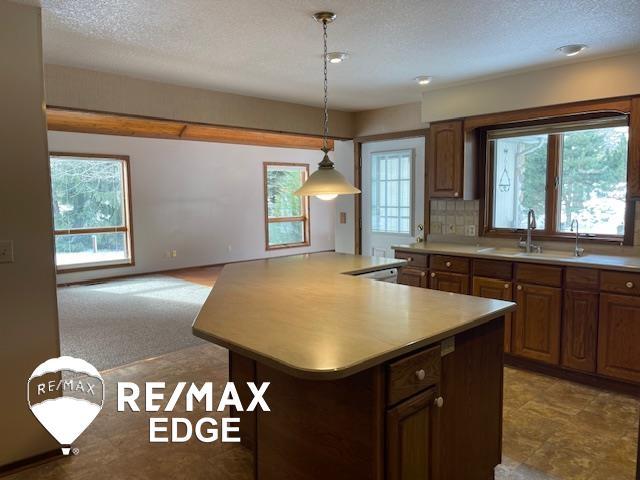 kitchen featuring tasteful backsplash, sink, a center island, and a textured ceiling