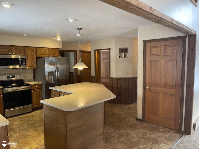 kitchen featuring stainless steel appliances, a kitchen island, hanging light fixtures, and a textured ceiling