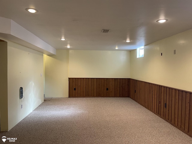 basement with light carpet and wooden walls