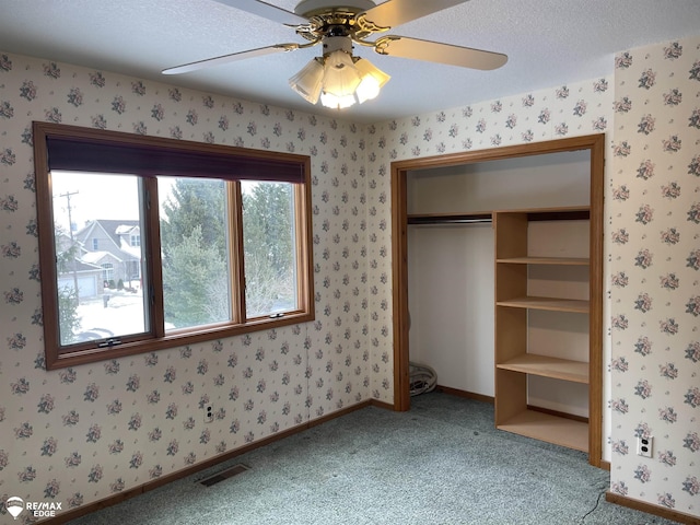 unfurnished bedroom featuring ceiling fan, carpet, a textured ceiling, and a closet