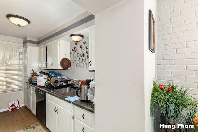 kitchen with brick wall, dark hardwood / wood-style floors, white cabinetry, dishwasher, and sink