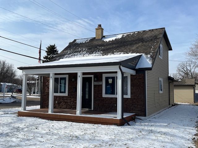 snow covered back of property with covered porch