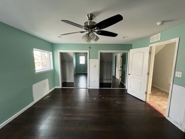 unfurnished bedroom featuring baseboards, wood finished floors, and visible vents