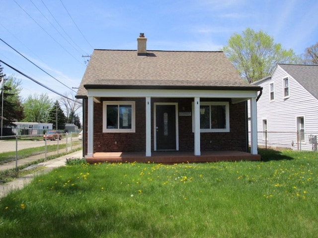 back of house featuring a porch, fence, a yard, and a chimney