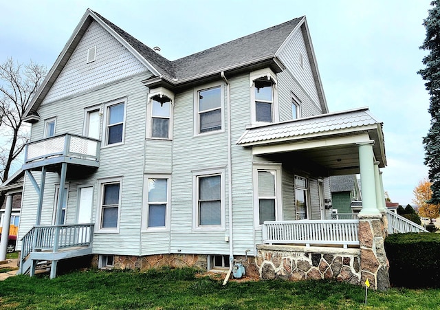 exterior space with a balcony, a yard, and covered porch