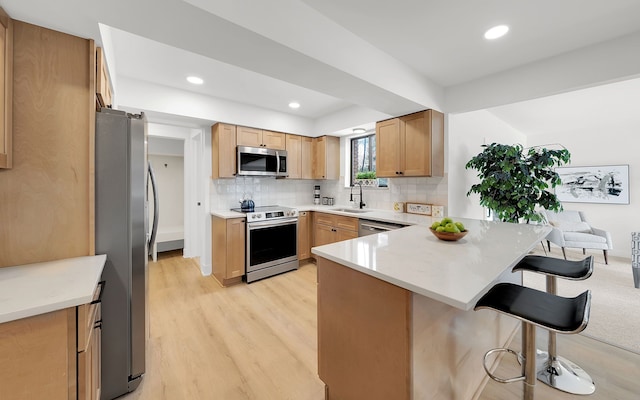 kitchen with a breakfast bar, sink, kitchen peninsula, stainless steel appliances, and backsplash