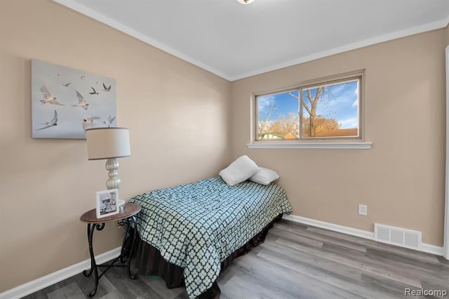 bedroom with crown molding and wood-type flooring