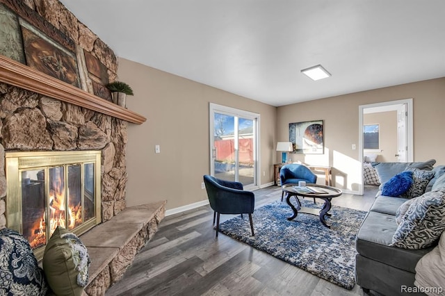 living room with a stone fireplace and hardwood / wood-style floors