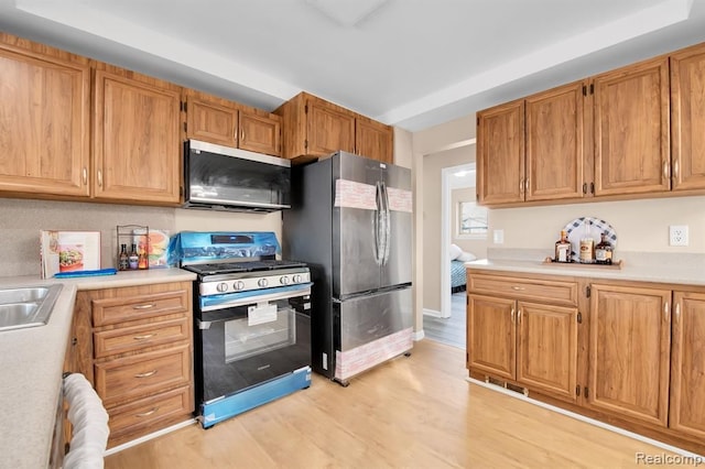 kitchen featuring appliances with stainless steel finishes, sink, and light hardwood / wood-style flooring