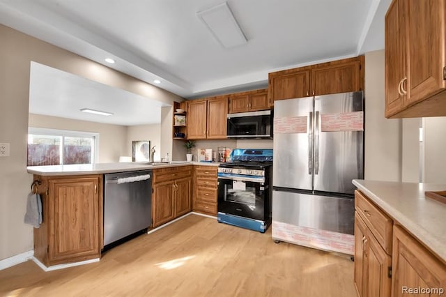 kitchen with stainless steel appliances, sink, light hardwood / wood-style flooring, and kitchen peninsula