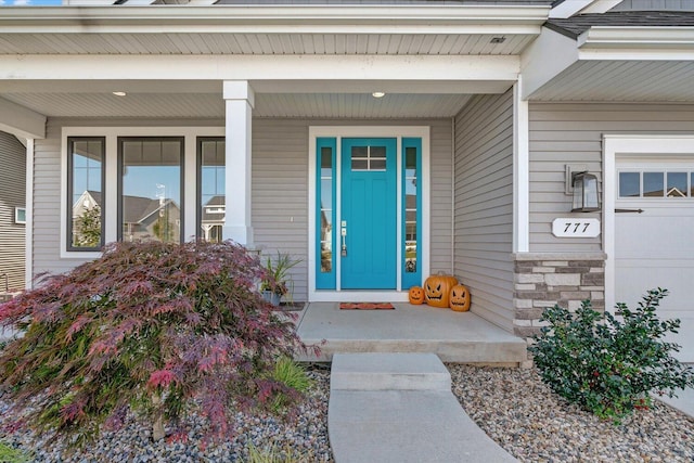 view of exterior entry with a garage and covered porch