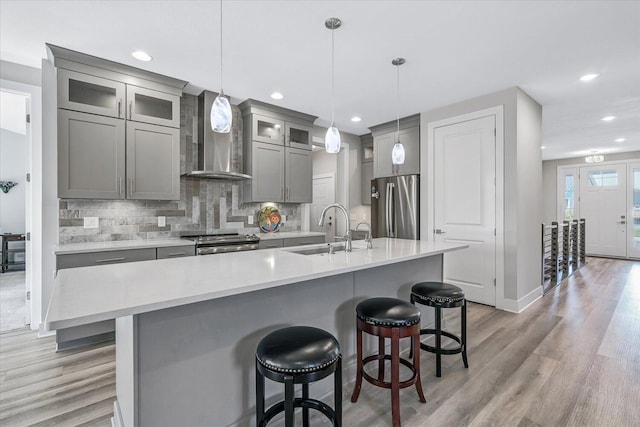 kitchen with stainless steel appliances, decorative light fixtures, a kitchen island with sink, and sink