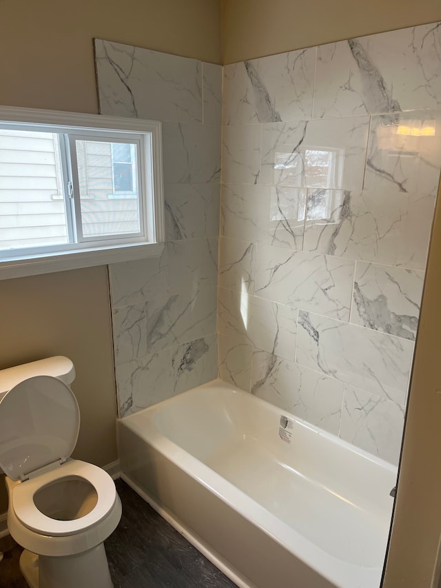 bathroom featuring tiled shower / bath combo and toilet