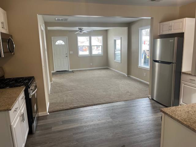 kitchen with stone counters, white cabinets, dark colored carpet, ceiling fan, and stainless steel appliances