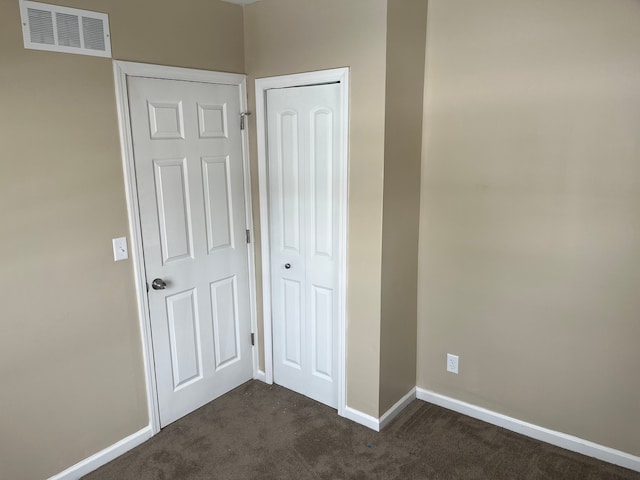 unfurnished bedroom featuring a closet and dark colored carpet