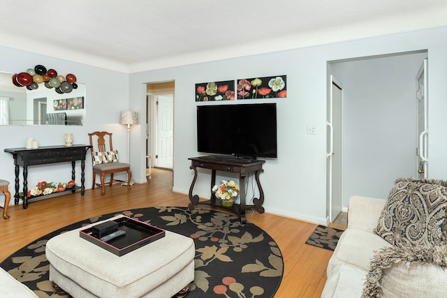 living room with a textured ceiling, baseboards, and wood finished floors