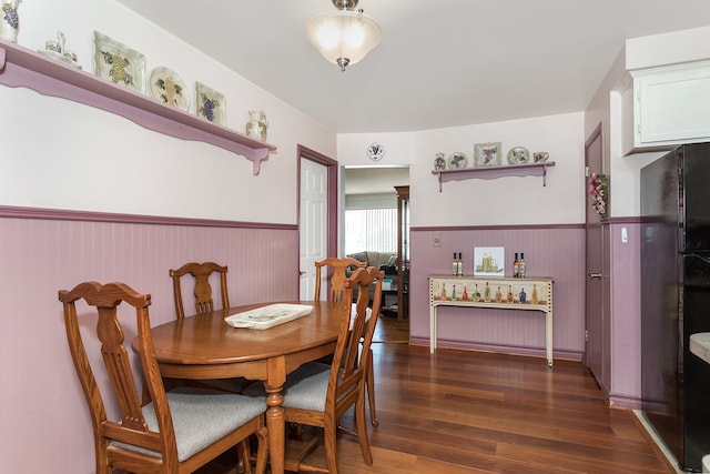 dining room featuring dark wood-type flooring and a wainscoted wall