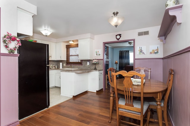 dining room with dark wood-style flooring, wainscoting, and visible vents