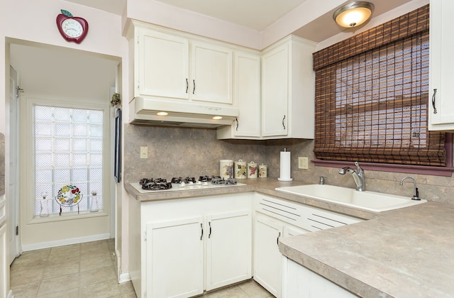 kitchen featuring white gas stovetop, tasteful backsplash, white cabinets, under cabinet range hood, and a sink