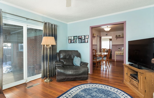 living area featuring dark wood-style floors, visible vents, and ornamental molding