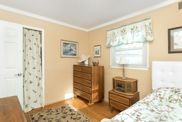 bedroom with ornamental molding, light wood finished floors, and visible vents