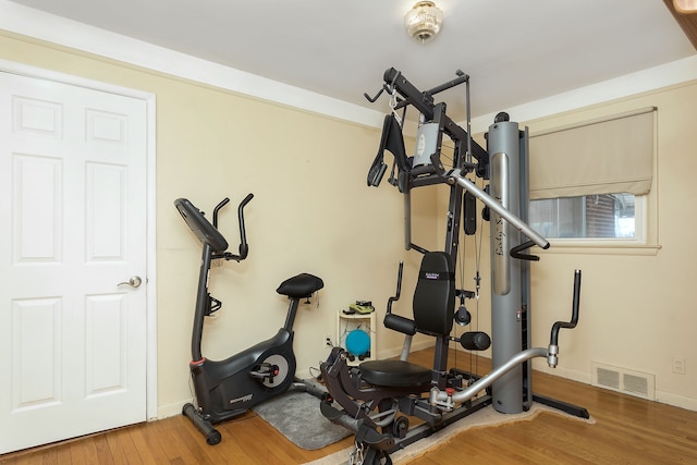 workout room with wood finished floors, visible vents, and baseboards