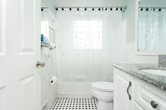 bathroom featuring tile patterned flooring, tile walls, toilet, and vanity