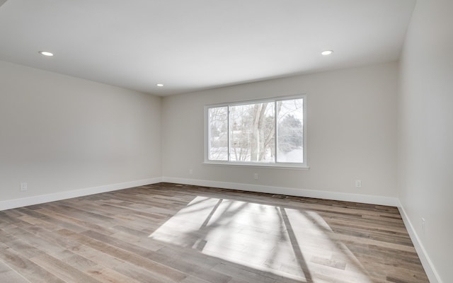 unfurnished room featuring recessed lighting, light wood-type flooring, and baseboards