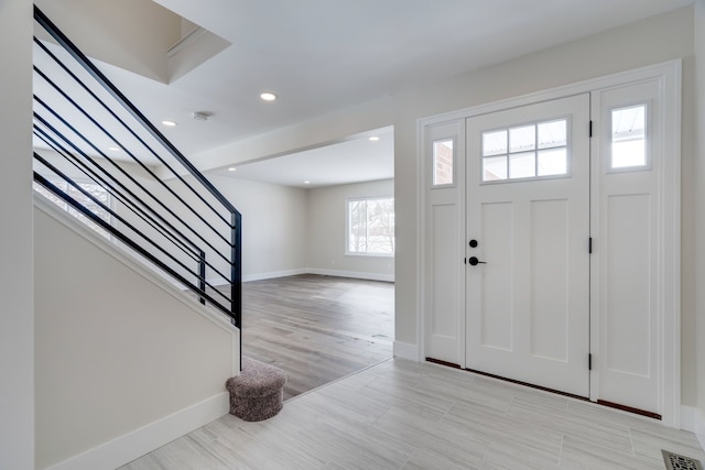 foyer entrance with light wood finished floors, recessed lighting, visible vents, baseboards, and stairs