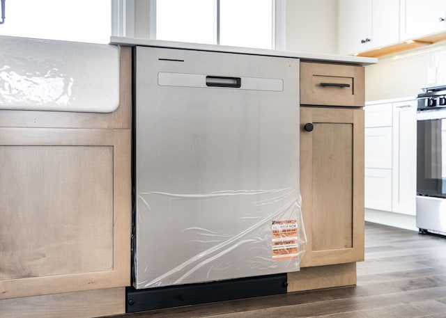 details featuring dark wood finished floors, light countertops, stainless steel dishwasher, light brown cabinetry, and wall oven