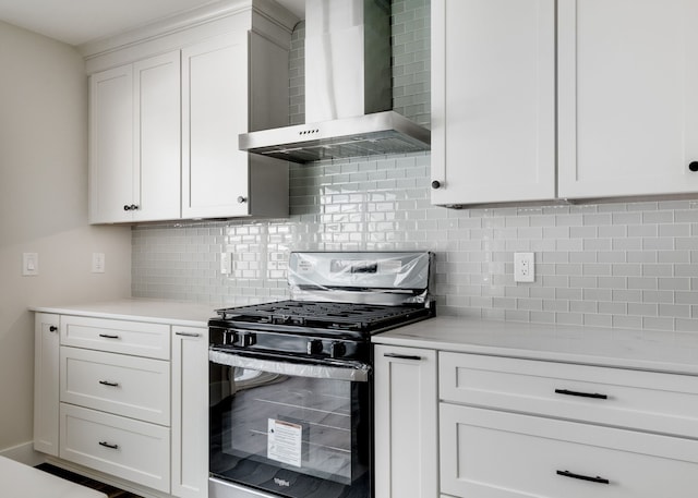 kitchen with stainless steel range with gas cooktop, light countertops, wall chimney range hood, and white cabinetry