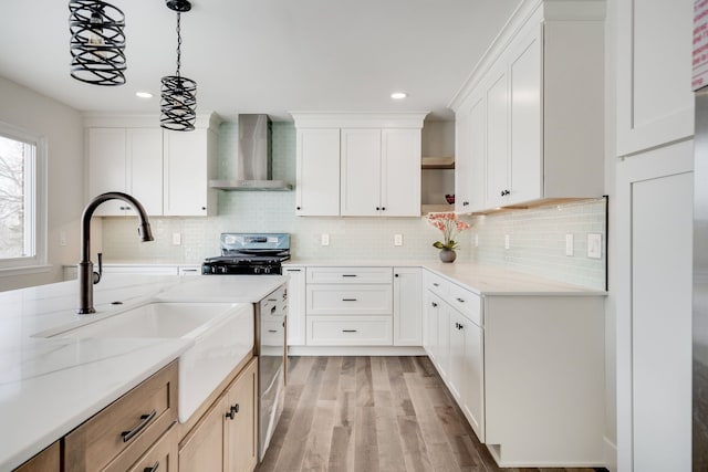 kitchen with wall chimney range hood, stove, and white cabinetry