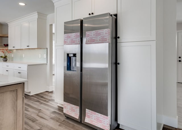 kitchen with light wood finished floors, decorative backsplash, stainless steel fridge with ice dispenser, white cabinetry, and open shelves