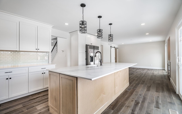 kitchen featuring stainless steel fridge, white cabinetry, a large island, and a barn door