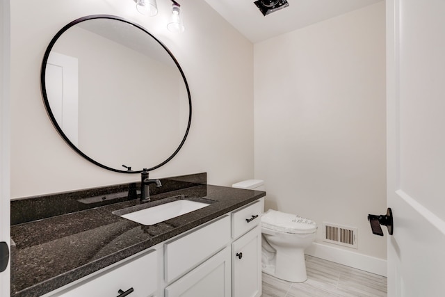 half bath with visible vents, vanity, toilet, and baseboards