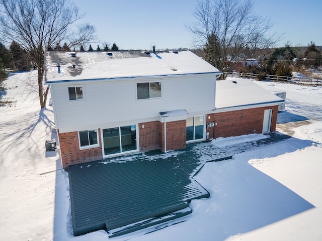 snow covered rear of property with fence and brick siding