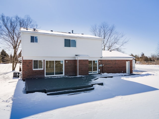 snow covered back of property featuring brick siding